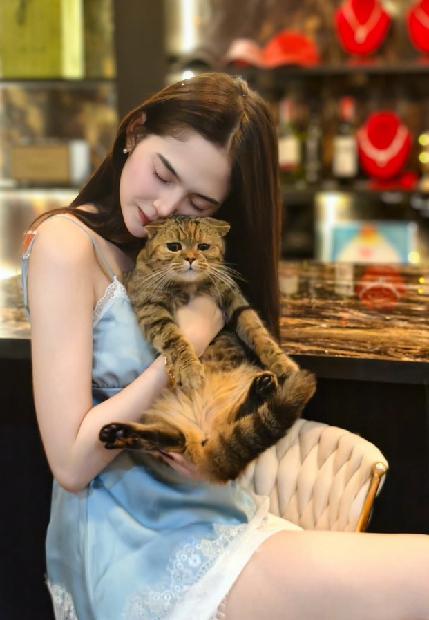 สาวไทยอุ้มแมวในร้านตกแต่งโทนอบอุ่น