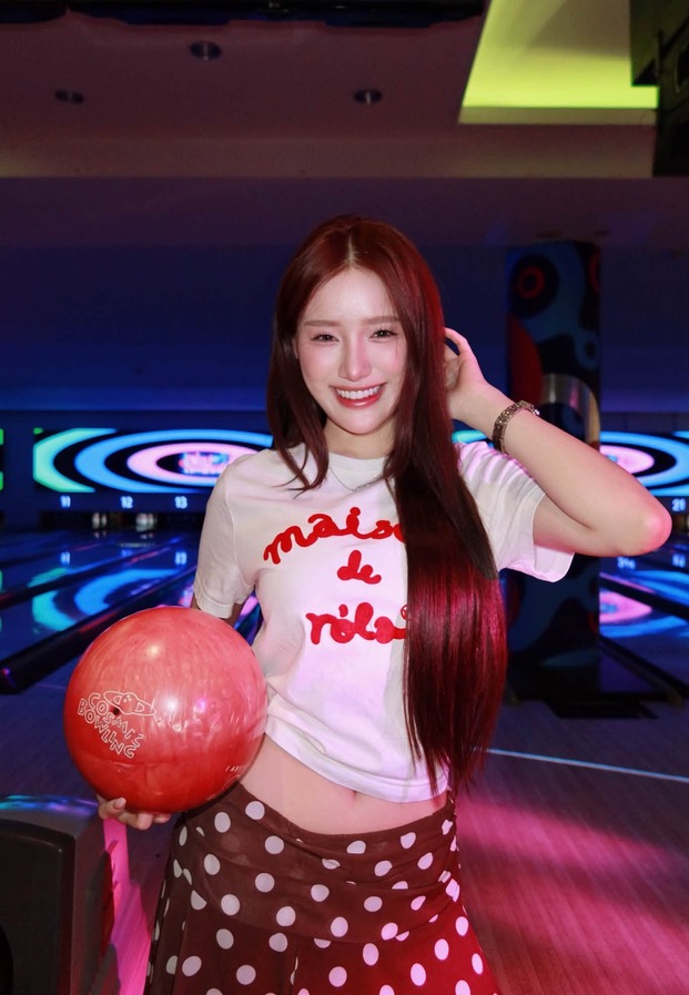 ขนม Khanomwws ถือลูกโบว์ลิ่งสีแดงในเลนโบว์ลิ่ง