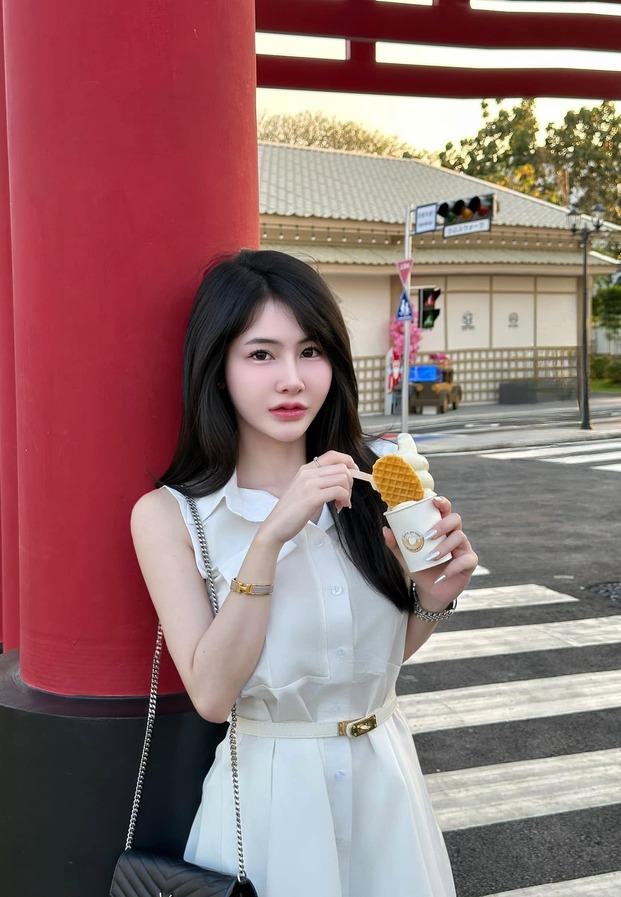 Cholthida Phonsan ในเดรสสั้นสีขาวถือเครปไอศกรีมหน้าเสาสถานีญี่ปุ่น