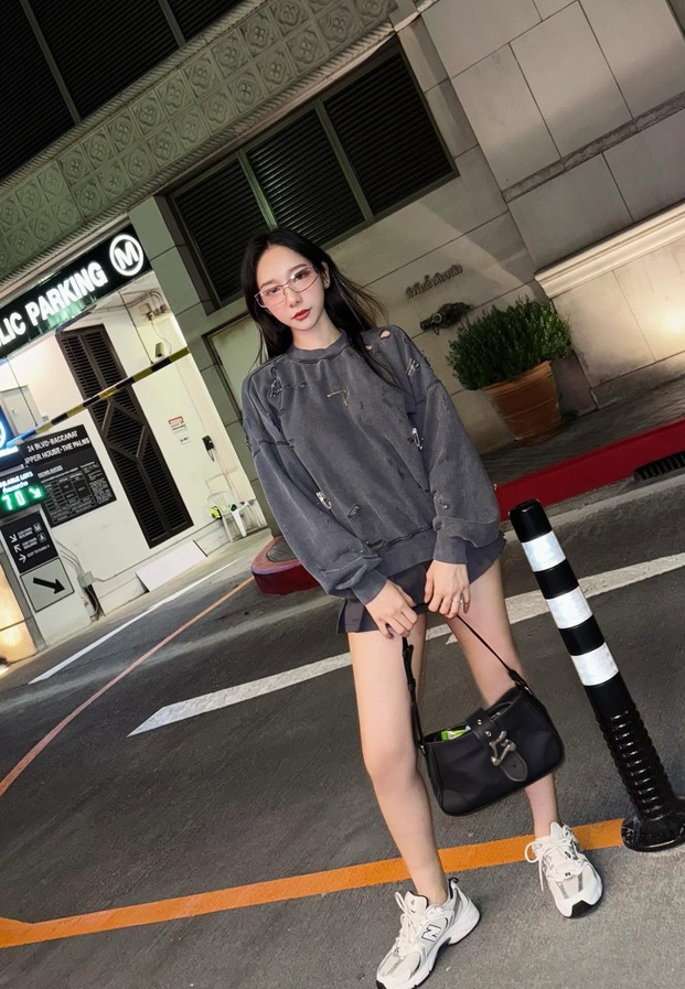 สเวตเตอร์สีเทาตัวโคร่งกับรองเท้าผ้าใบหน้าอาคารจอดรถ